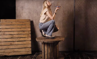 a young woman smoking while kneeling on a wooden spool