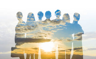 an outline of seven people over a sunset